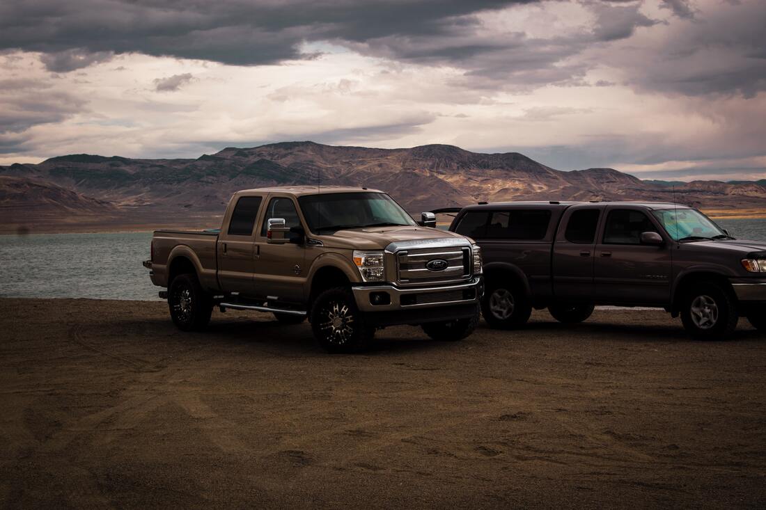 Two pick-up truck parked in the wilderness with great sceneries   